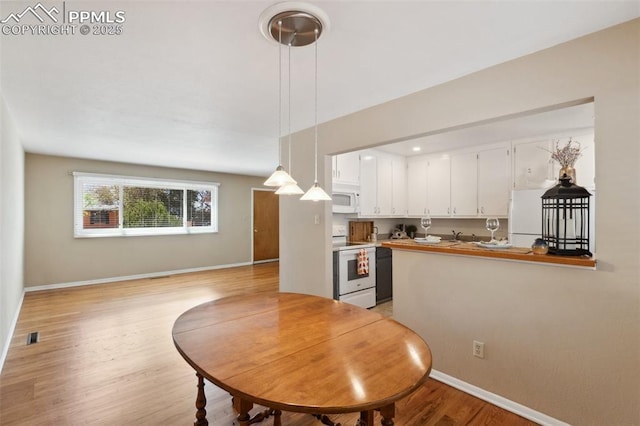 2928 Drakestone Dr, Colorado Springs, CO 80909 - kitchen with light wood finished floors, white appliances, white cabinetry, baseboards, and pendant lighting