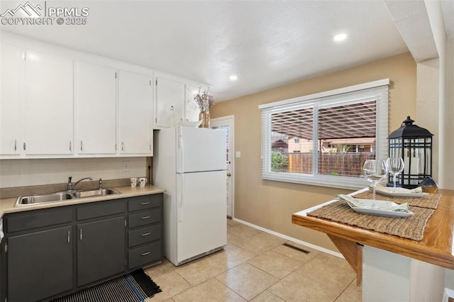 2928 Drakestone Dr, Colorado Springs, CO 80909 - kitchen featuring a sink, baseboards, light tile patterned floors, freestanding refrigerator, and white cabinetry