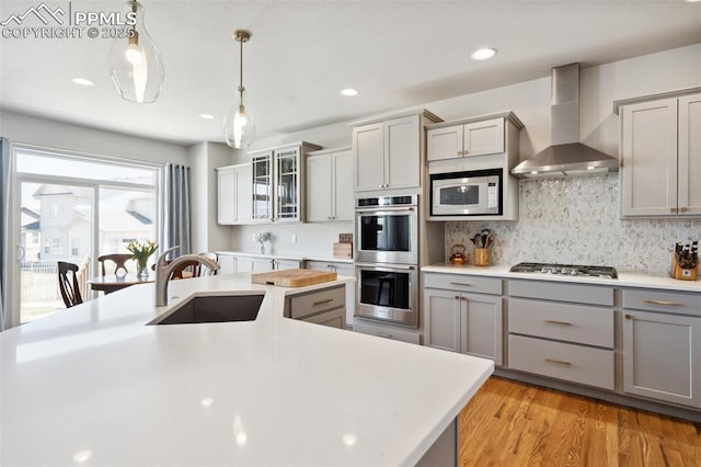 12980 Stone Valley Dr, Peyton, CO 80831 - kitchen with wall chimney range hood, a sink, appliances with stainless steel finishes, gray cabinets, and light countertops