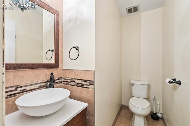 bathroom with vanity, tile patterned flooring, toilet, visible vents, and tile walls