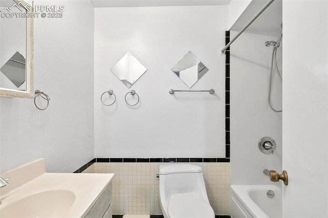 full bathroom featuring vanity, toilet, wainscoting, tile walls, and shower / bathing tub combination
