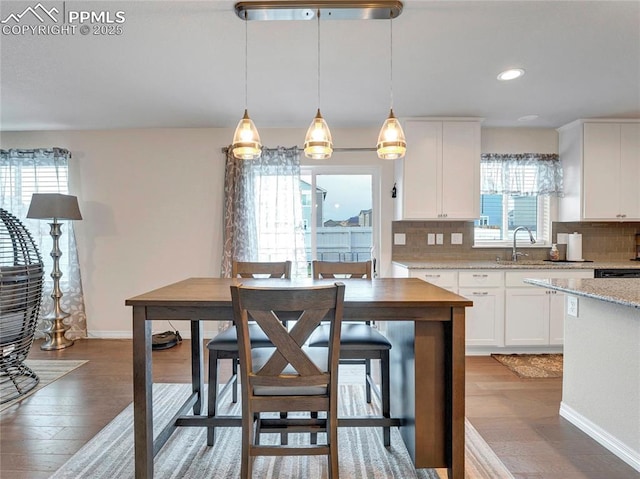 kitchen featuring hanging light fixtures, light wood-type flooring, and backsplash