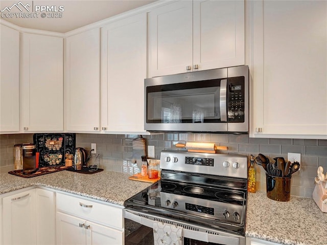 kitchen with white cabinets, light stone counters, appliances with stainless steel finishes, and tasteful backsplash