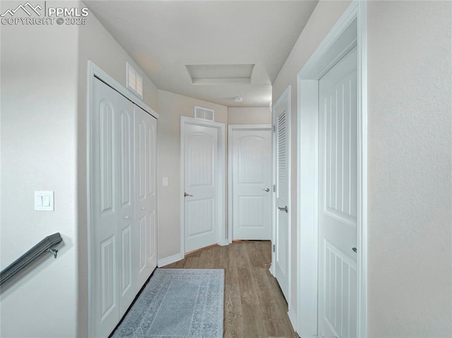 hallway featuring visible vents and wood finished floors