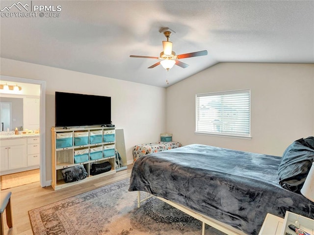bedroom with connected bathroom, vaulted ceiling, a sink, a ceiling fan, and light wood-style floors