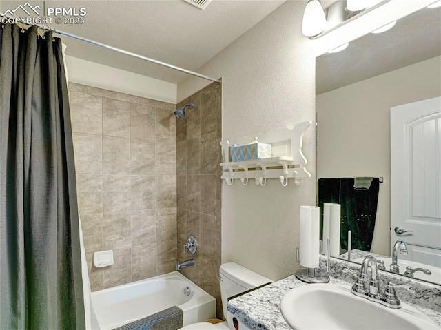 bathroom featuring a textured wall, shower / tub combo with curtain, toilet, and vanity