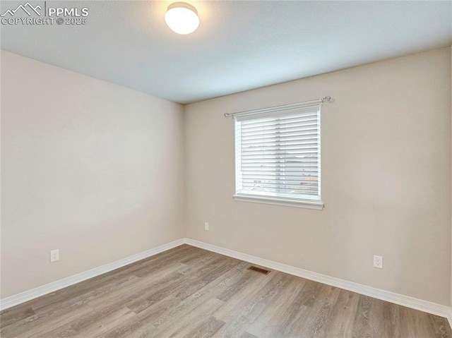 spare room featuring baseboards, visible vents, and light wood-style floors