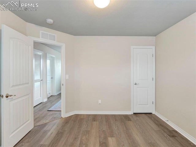 spare room featuring baseboards, visible vents, and wood finished floors