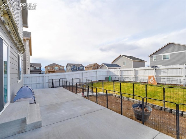 view of patio featuring a fenced backyard, a residential view, and a vegetable garden