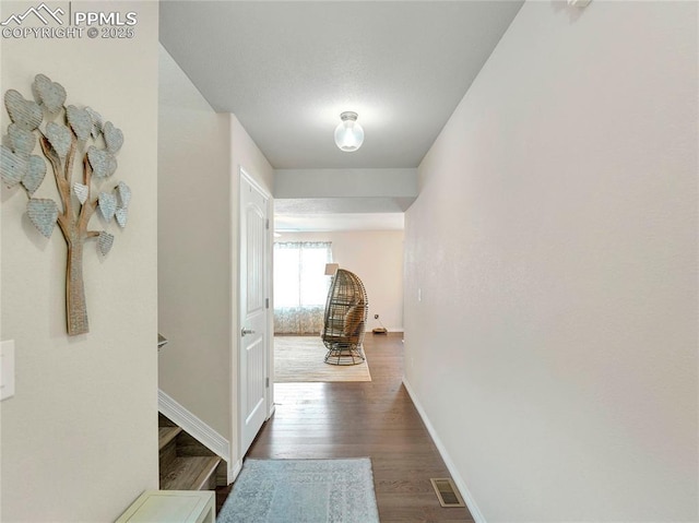 hall with baseboards, visible vents, and dark wood finished floors