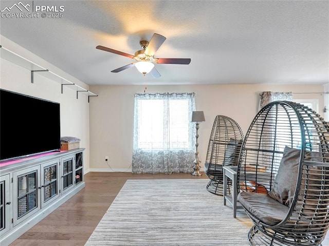 interior space with baseboards, wood finished floors, ceiling fan, and a textured ceiling