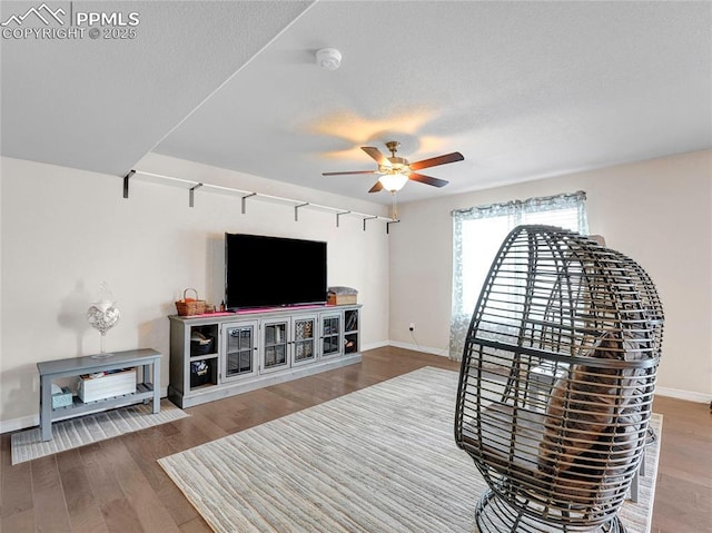 sitting room with baseboards, wood finished floors, and ceiling fan