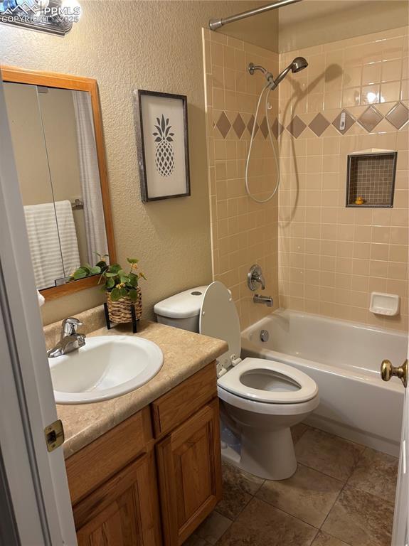 full bathroom with a textured wall, toilet, vanity, and bathing tub / shower combination