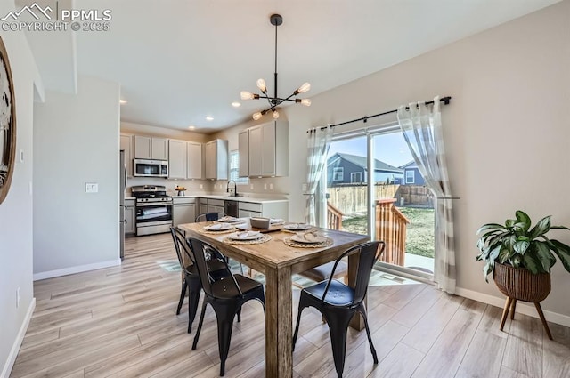 dining space featuring a chandelier, light wood-style flooring, baseboards, and a healthy amount of sunlight