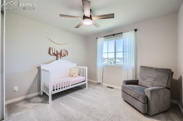 bedroom featuring visible vents, baseboards, a ceiling fan, a crib, and carpet