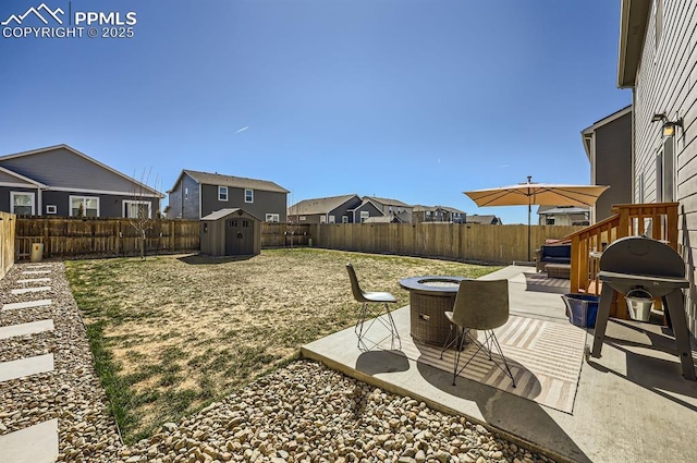 view of yard featuring a fenced backyard, an outdoor structure, a patio, a storage unit, and a fire pit