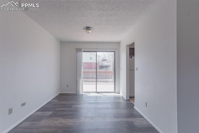 spare room featuring a textured ceiling, baseboards, and wood finished floors