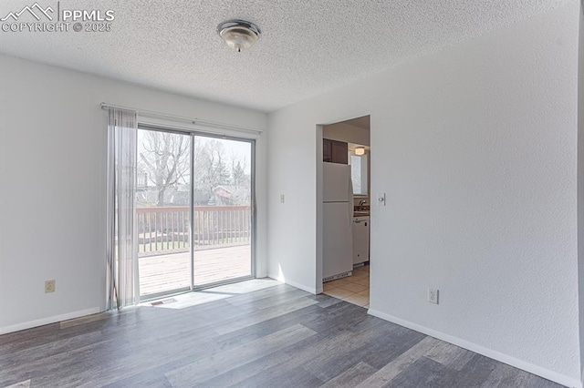 unfurnished room with a textured wall, baseboards, wood finished floors, and a textured ceiling