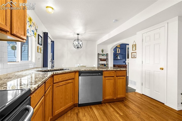 2951 Poughkeepsie Dr, Colorado Springs, CO 80916 - kitchen with a peninsula, light wood-style flooring, brown cabinetry, stainless steel dishwasher, and a sink