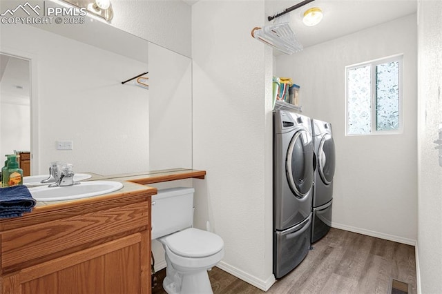 2951 Poughkeepsie Dr, Colorado Springs, CO 80916 - bathroom featuring vanity, separate washer and dryer, visible vents, and wood finished floors