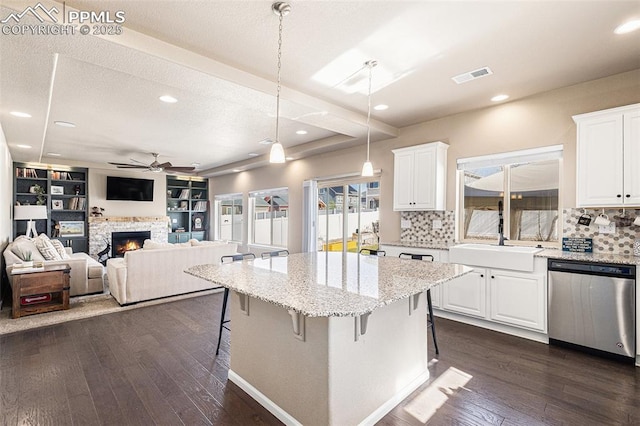 kitchen with white cabinets, ceiling fan, a kitchen breakfast bar, tasteful backsplash, and stainless steel dishwasher