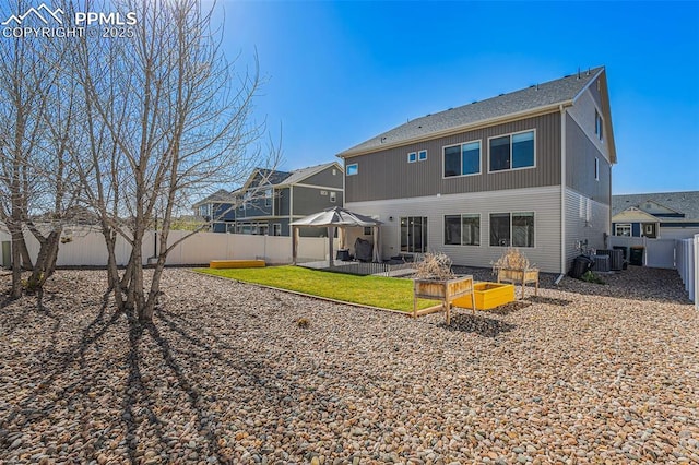 rear view of house featuring roof with shingles, a fenced backyard, a garden, central air condition unit, and a patio