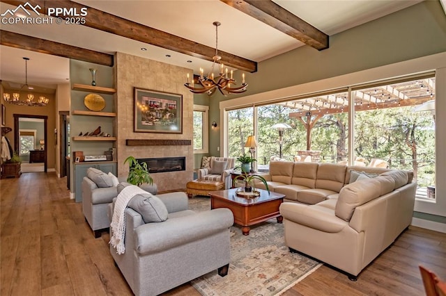 18383 Lazy Summer Way, Monument, CO 80132 - living room featuring a chandelier, wood finished floors, beamed ceiling, a fireplace, and baseboards