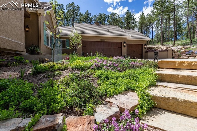 18383 Lazy Summer Way, Monument, CO 80132 - view of property exterior featuring a tiled roof, stucco siding, a garage, and a chimney