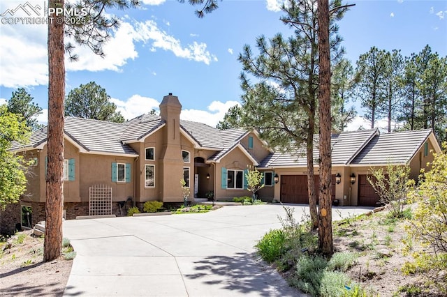 18383 Lazy Summer Way, Monument, CO 80132 - ranch-style home with a chimney, concrete driveway, an attached garage, a tile roof, and stucco siding