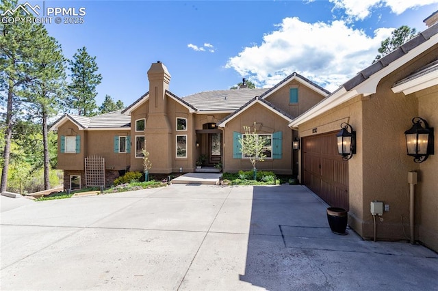 18383 Lazy Summer Way, Monument, CO 80132 - view of front of home featuring concrete driveway, a chimney, a garage, stucco siding, and a tile roof