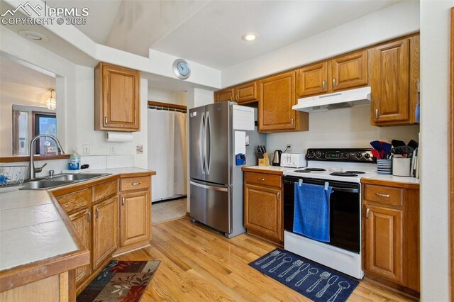 6627 Wagon Ridge Dr, Colorado Springs, CO 80923 - kitchen with a sink, freestanding refrigerator, light wood-style floors, under cabinet range hood, and white electric range