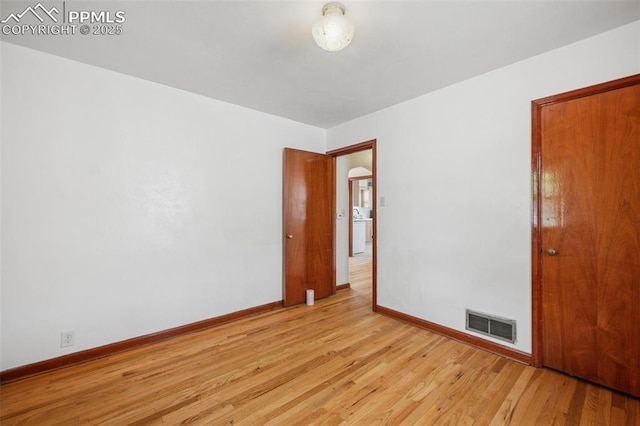 empty room with baseboards, light wood finished floors, washer / clothes dryer, and visible vents