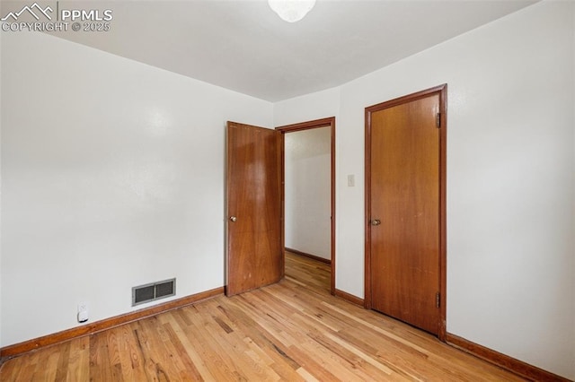 unfurnished bedroom with light wood-type flooring, visible vents, and baseboards
