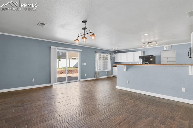 unfurnished living room featuring baseboards, ornamental molding, dark wood-type flooring, and visible vents