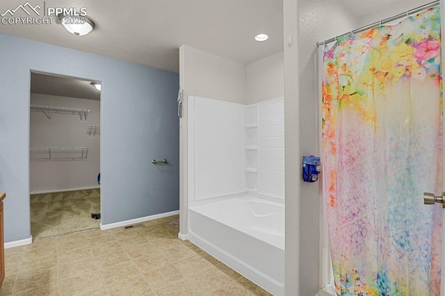 full bathroom with baseboards, a shower with curtain, a walk in closet, and a bathing tub