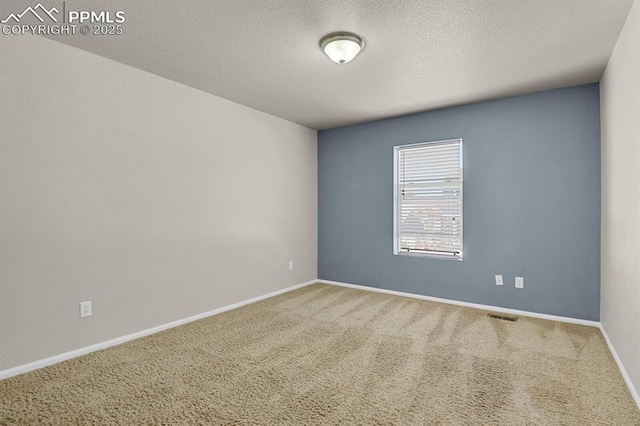 carpeted empty room featuring baseboards, a textured ceiling, and visible vents