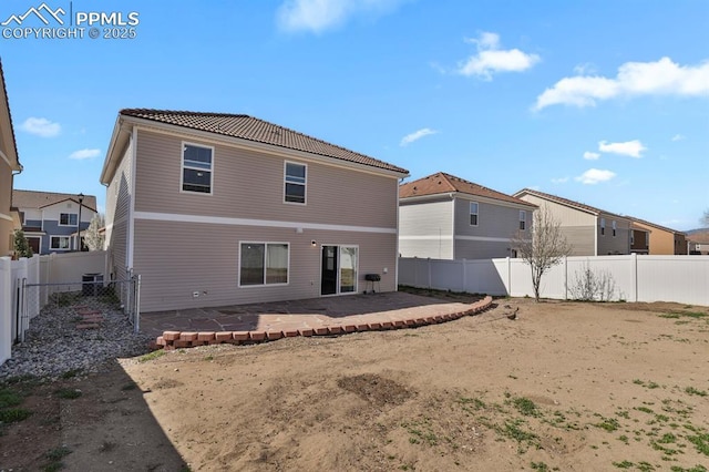 rear view of house with a fenced backyard, a tiled roof, a residential view, and a patio
