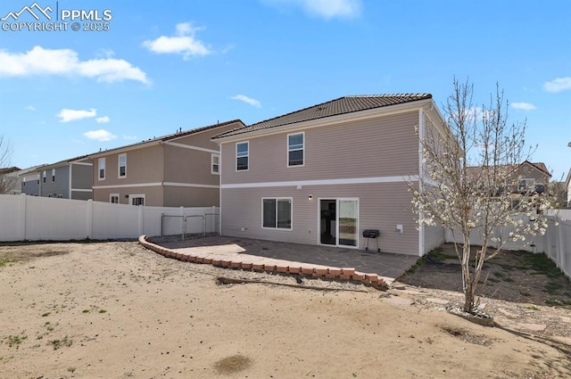 back of property with a tile roof, a fenced backyard, and a patio