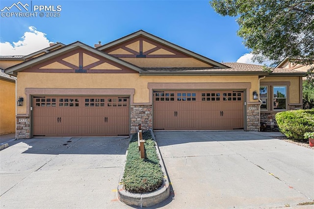 craftsman-style home with concrete driveway, stucco siding, and stone siding
