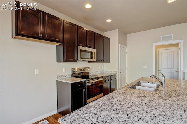 kitchen with visible vents, baseboards, a sink, appliances with stainless steel finishes, and light stone counters