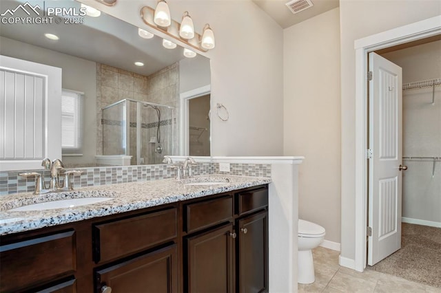 bathroom featuring a sink, visible vents, a shower stall, and a walk in closet
