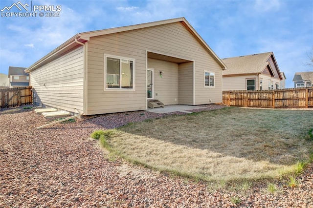 back of property with a patio area, entry steps, a fenced backyard, and a lawn