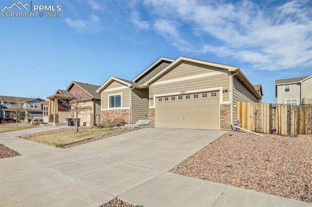 craftsman house with an attached garage, driveway, fence, and stone siding