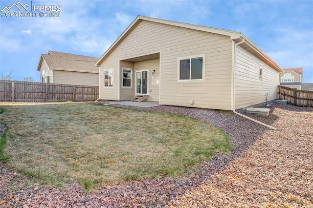 rear view of property with entry steps, a fenced backyard, a patio area, and a lawn