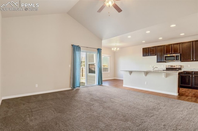 interior space with open floor plan, appliances with stainless steel finishes, dark brown cabinets, recessed lighting, and ceiling fan with notable chandelier
