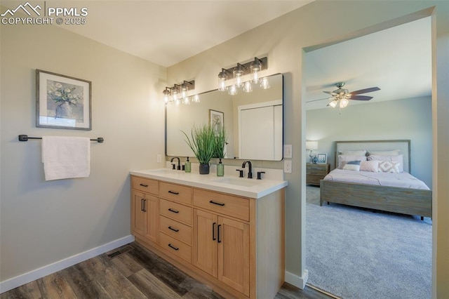 ensuite bathroom featuring a sink, double vanity, a ceiling fan, baseboards, and ensuite bathroom
