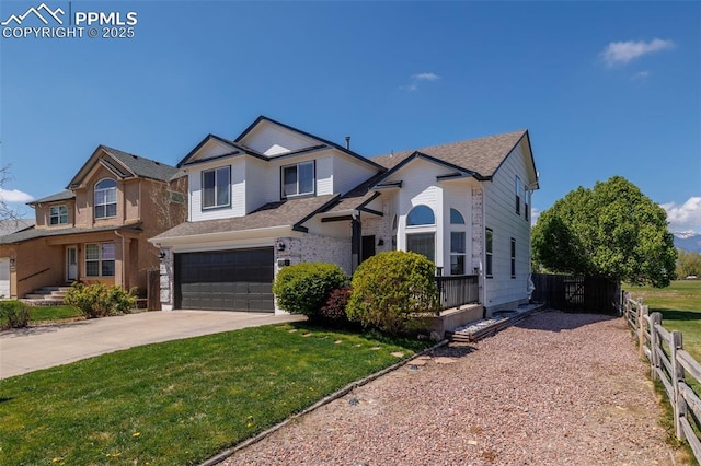 traditional-style house with an attached garage, a front lawn, fence, and driveway