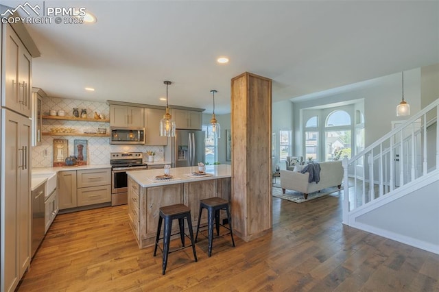 kitchen with decorative backsplash, open shelves, wood finished floors, light countertops, and stainless steel appliances