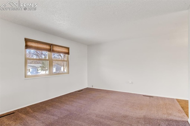 spare room featuring carpet flooring, visible vents, a textured ceiling, and baseboards