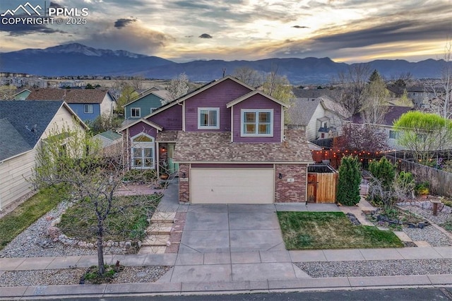 traditional-style home with fence, a mountain view, driveway, and brick siding